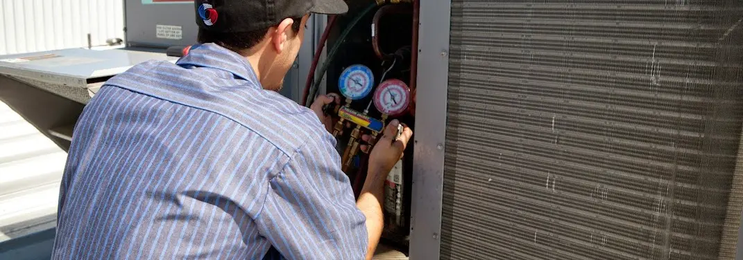 HVAC technician servicing a condenser unit in Hot Springs